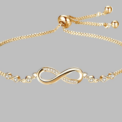 Gold bracelet with infinity symbol and small crystals on a gray background